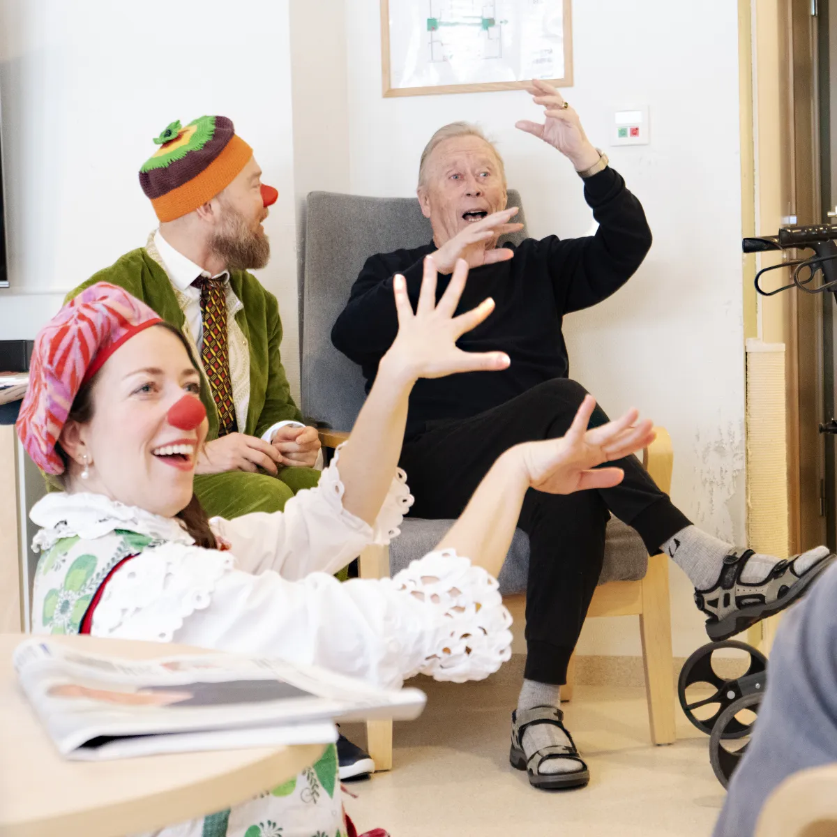 Fru Eple og klovnekollega deler et latterøyeblikk med en beboer