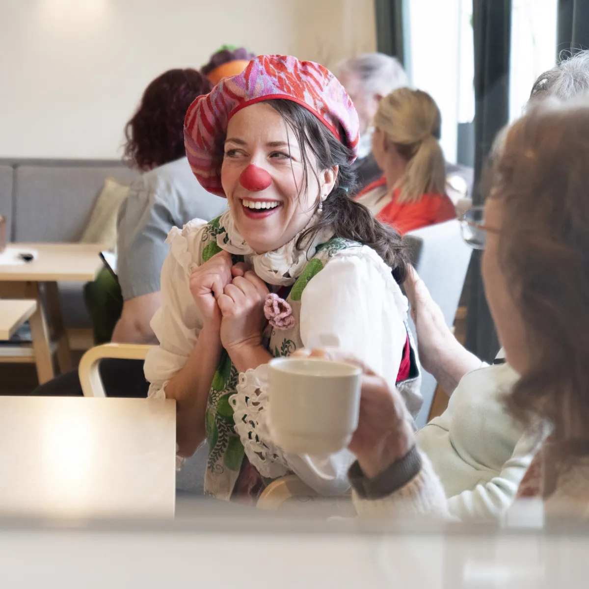 Fru Eple i samtale med en beboer over en kopp kaffe